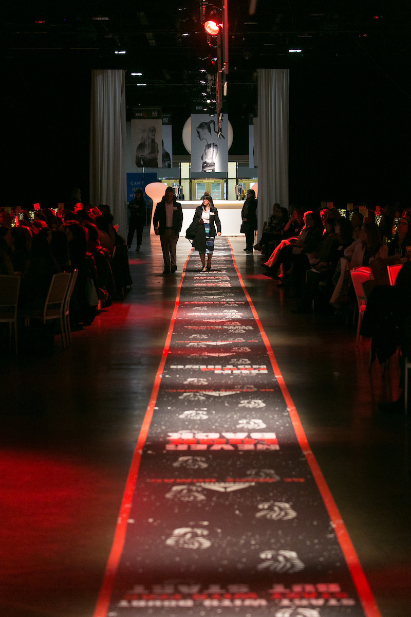 Guests walking the red-lit runway through the ballroom